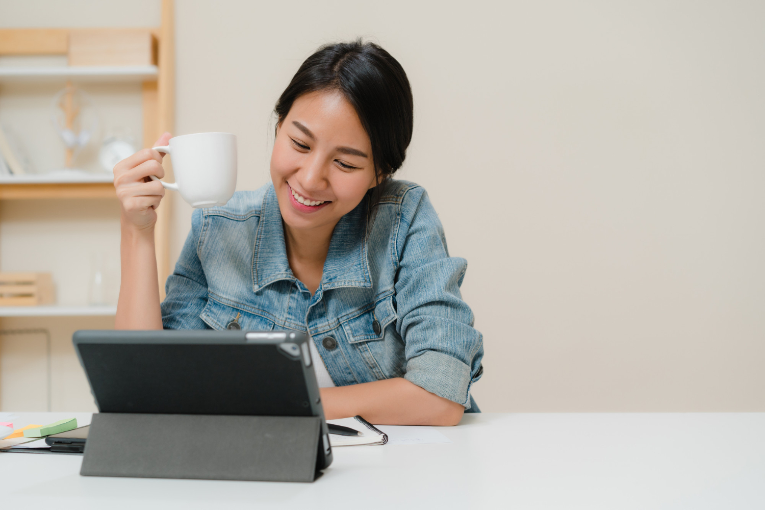 Female teacher using tablet with coffee cup